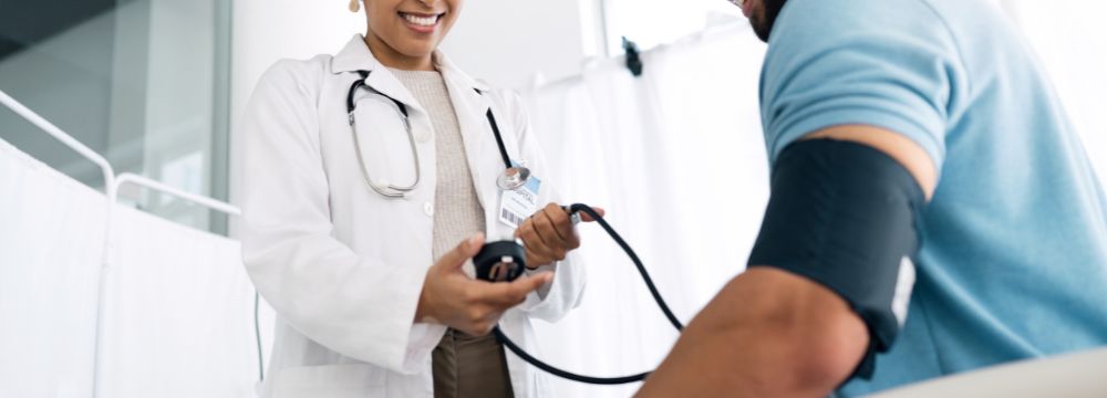 Doctor taking male patients blood pressure in hospital setting 